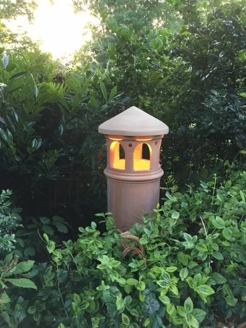 Eine Terracotta-Standleuchte vollständig und beleuchtet im Garten